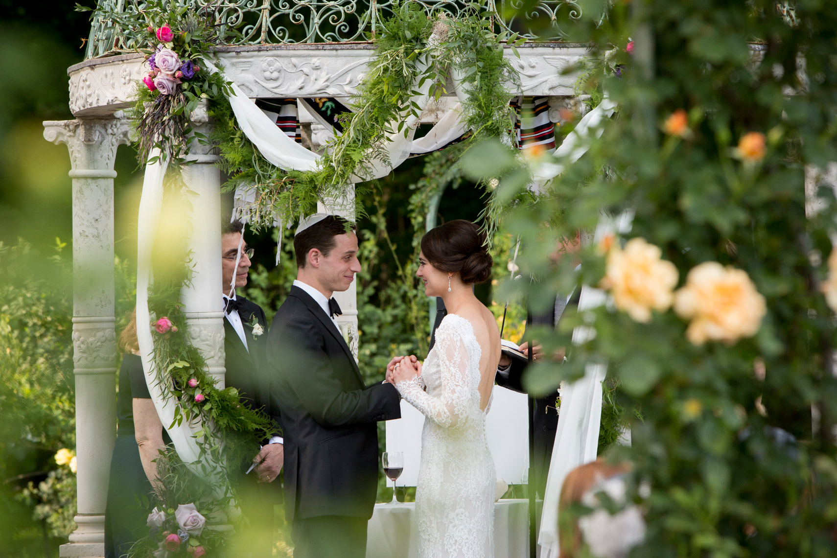 bride-groom-exchanging-rings-ceremony-Lyndhurst_Mansion-sarma-and-co