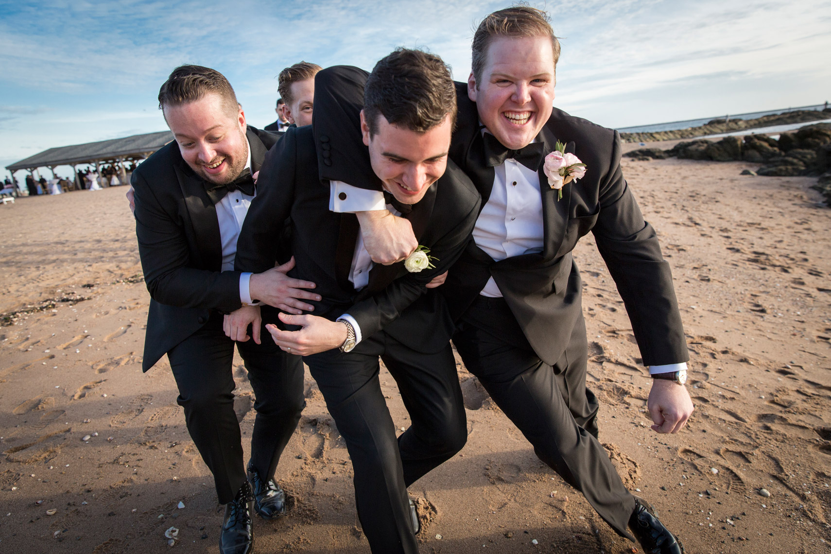 groom-being-tackled-groomsmen-beach-Carousel-Lighthouse-Point-CT-sarma-and-co